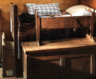 Hohes Elternbett mit daruntergeschobenem Ausziehbett (Guitschi) auf Rädern.