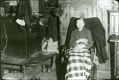 Aufnahme einer gichtkranken Frau in ihrer Stube in Blatten, um 1915. Die Fotografie wurde von Karl Anneler (1886-1957) gemacht. Anneler war Kunstmaler und hielt sich ab 1906 regelmässig im Lötschental auf.